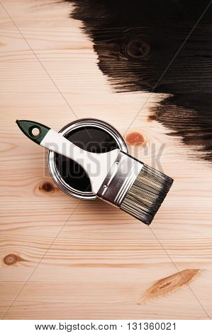 Paint brush on the can lying on wooden background. The surface is half - toned with red color.