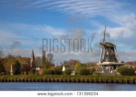 Windmill And Church In Small Village Of Woltersum