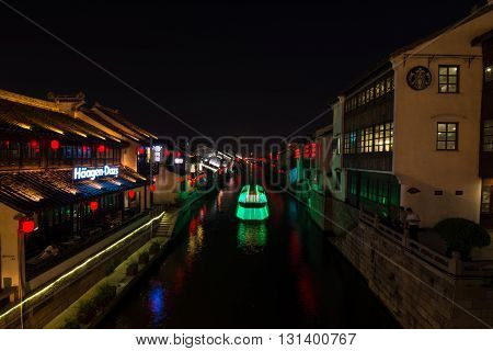 The water between the buildings city nightlife and the ship. Illuminated ship sails on the river between the illuminated houses. Night city and water