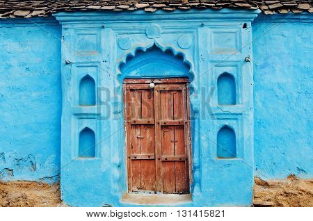 Blue painted traditional rural house with closed wooden door in Madhya Pradesh, India