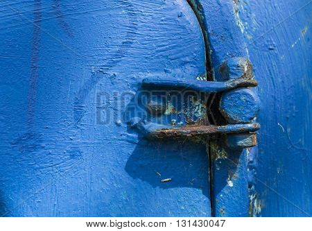Old blue rusty door hinge in sunlight