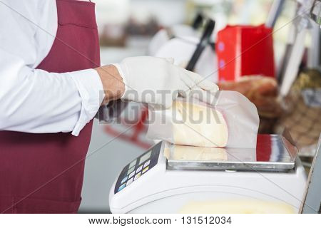 Salesman Wrapping Cheese On Weight Scale