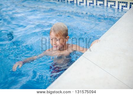 Cute little boy bathes in a pool