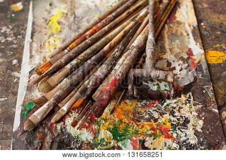 Art materials. Different bedraggled used brushes on gray sloppy surface