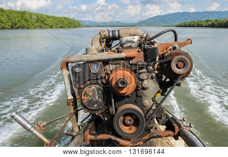 The engine of a long-tail boat with boat wake and tropical mangrove forest background in Phang Nga Bay National Park Thailand