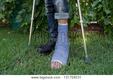 Young Man With A Leg Cast In A Garden