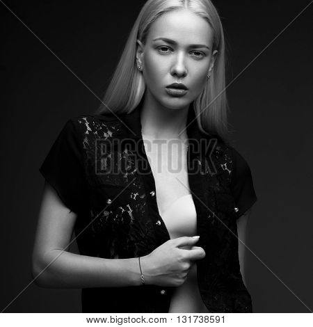 sexy fashion model with long hair, young European attractive, beautiful eyes, full lips, perfect skin is posing in studio for glamour vogue test photo shoot showing different poses. Picture taken in the studio on a gray background. Black and white photo