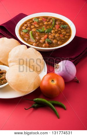 spicy chick peas also known as Chola Masala or Chana Masala or Chole served with fried puri, pickle and green salad