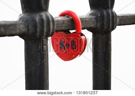 Closed red padlock in the form of heart locked on bridge