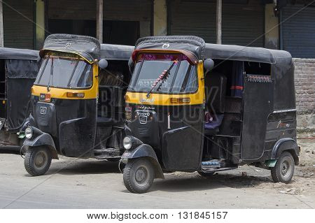 SRINAGAR INDIA - JULE 02 2015: Auto rickshaw taxis on a road in Kashmir India. These iconic taxis have recently been fitted with CNG powered engines in an effort to reduce pollution