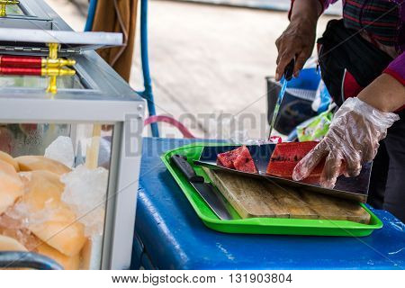 Woman Selling Watermelonwatermelon cut with a knife