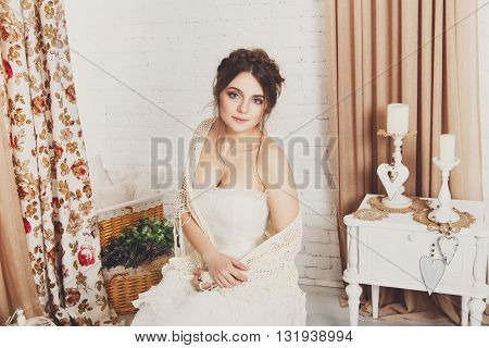 Wedding dress fashion. Beautiful young bride in vintage crochet shawl, shabby chic champagne color wedding dress. Rustic wedding dress at model, in decorated interior, studio shot, high key.