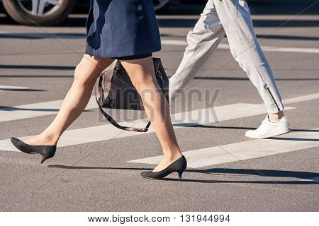 two pedestrians walking on a pedestrian crossing closeup