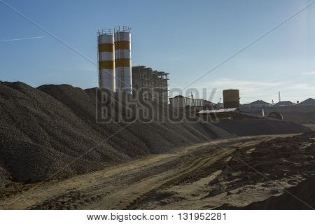 Quarry crusher plant in sand and gravel production. Cement production factory on mining quarry. Conveyor belt of heavy machinery loads stones and gravel. Construction works, machinery factory