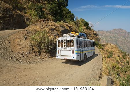 AXUM, ETHIOPIA - JANUARY 23, 2010: Tourist bus pass by the narrow gravel mountain road in Axum, Ethiopia.