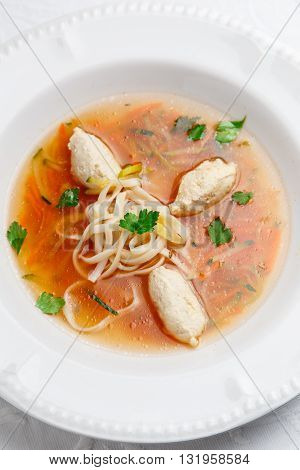 Tasty chicken soup with noodles and vegetables in white bowl