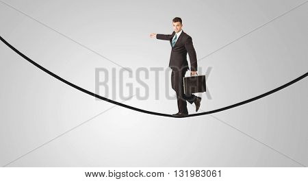 A confident smiling salesman balancing on black wire in clear grey empty space concept