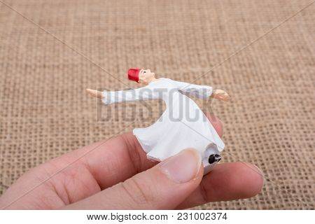 Hand Holding A White Color Sufi Dervish Figurine In Hand