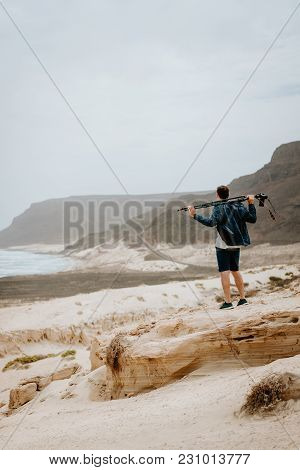 Photographer With Camera Looking For Motive Of Unique Landscape. Sand Dunes And Volcanic Cliffs On T