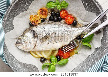 Fish Gilt-head Bram, Cooked In A Pan With Vegetables And Lemon, Black Olives. Fresh Basil . Healthy 
