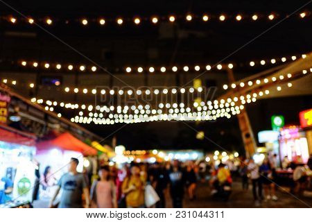 Blurred A Night Market At Night With People Walking Around And Bokeh Light