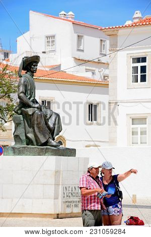 Lagos, Portugal - June 9, 2017 - A Couple Looking At A Map And Pointing In Front Of The Statue Of In
