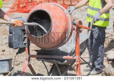 Construction Worker On A Cement / Concrete Mixer Doing Hard Job.