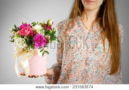 Girl Holding In Hand Rich Gift Bouquet. Composition Of Flowers In A Pink Hatbox. Tied With Wide Whit