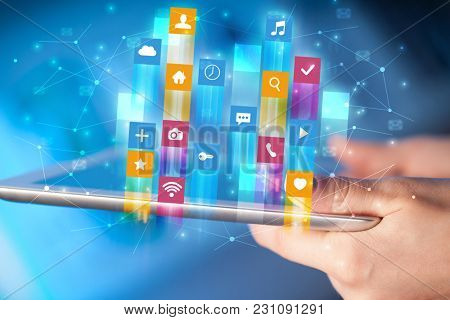 Businessman hand using tablet with flying application icons around