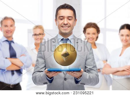 cryptocurrency, financial technology and business concept - smiling businessman with golden etherum coin and tablet pc over people on background