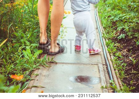 The Child Learns To Walk In The Park Barefoot On The Grass