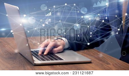 Businessman typing on laptop with linked reports charts grapghs around