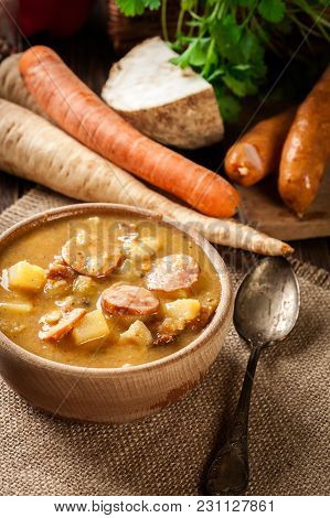 Wooden Bowl Of Split Pea Soup With Sausage And Potatoes