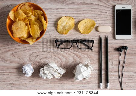 Workspace With Laptop,crumpled Paper And Bowl Of Chips On Wood Table. Bad Habits Concept