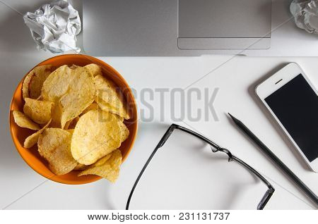Workspace With Laptop,crumpled Paper And Bowl Of Chips On Wood Table. Bad Habits Concept