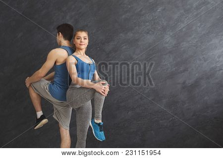 Couple Warming Up Legs Before Training, Standing Back To Back At Gym. Sporty Man And Woman Doing Str