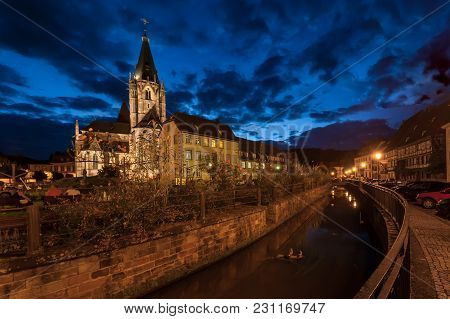 Church St. Peter Et Paul In Wissembourg, France On A Cloudy Night, Blue Sky, Canal