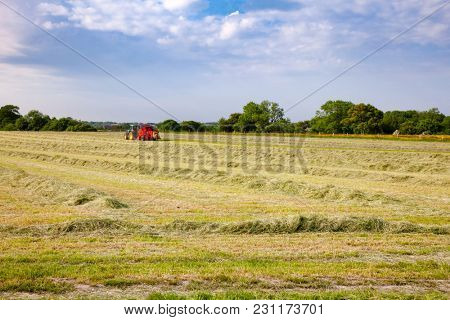 English rural landscape with  tractor collecting cut hay making silage bales Southern England UK