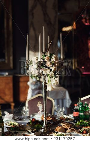 Pink Rose Petals Ligh Between White Candles Standing On The Dinner Table