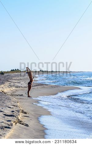 Young Beautiful Girl Perform Exercises On Gymnastics On The Shores Of The Black Sea