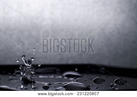 A Black And White Photograph Of A Drop Falling On The Black Plastic Lined Up In The Form Of A Human 