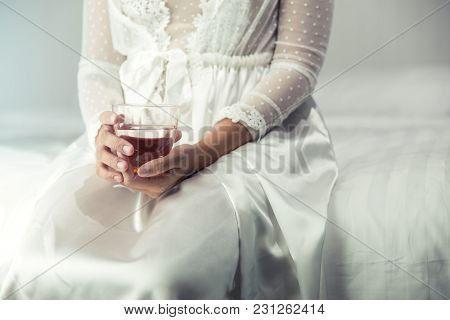 Female In White Nightwear Hand Holding A Glass Of Clean Water In The Bedroom