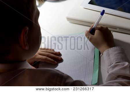 Close-up Of Boy Hand With Pencil Writing English Words By Hand On Traditional White Notepad Paper. B