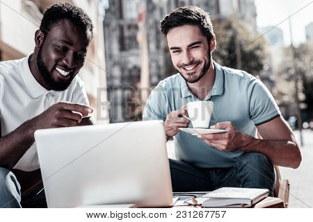 What Do You Think. Happy Young Men Smiling Cheerfully While Sitting Next To Each Other And Looking A