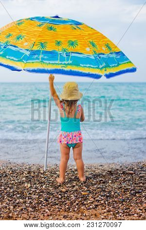 Child On The Beach Under An Umbrella