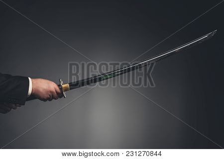 Cropped Shot Of Man Holding Katana Sword On Black