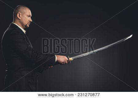 Side View Of Man In Suit With Katana Sword Isolated On Black