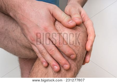 Man With Knee Pain Is Holding His Aching Leg - Body Pain Concept