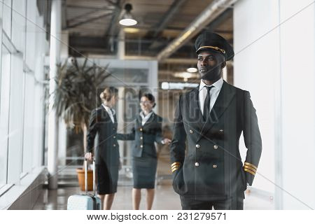 Thoughtful Young Pilot In Airport With Stewardesses Before Flight