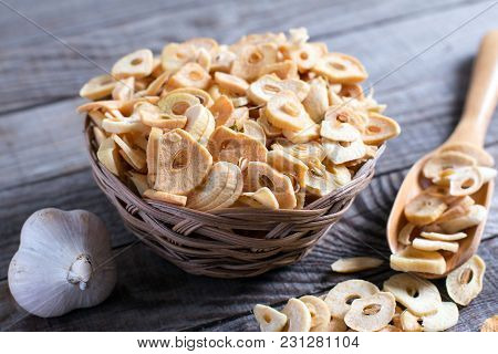 Bowl With Dried Garlic Flakes On Wooden Table